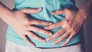 Frau mit Magen-Darm-Problemen. Chronische Magen-Darm-Störungen gehen oft mit einer gestörten Darmbarriere einher.